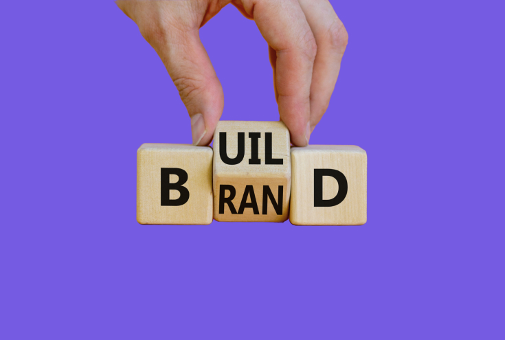 Build your brand symbol. Businessman turns wooden cubes and changes the word 'build' to 'brand'. Beautiful orange background. Build your brand and business concept.
